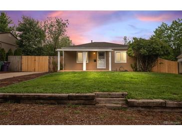 Charming single-story home featuring a covered porch, well-maintained lawn, and a rustic wooden retaining wall at 1865 S Knox Ct, Denver, CO 80219