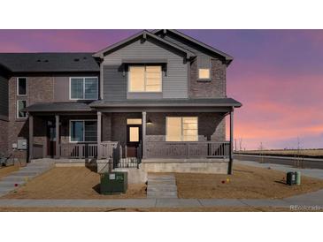 Charming two-story townhome featuring a covered porch and a mix of brick and siding for a modern aesthetic at 6504 N Malaya St, Aurora, CO 80019