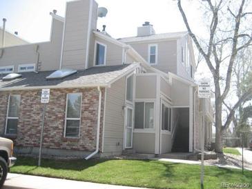 Tan townhouse featuring a brick facade, green lawn, and well-lit exterior at 4931 Garrison St # 204G, Wheat Ridge, CO 80033