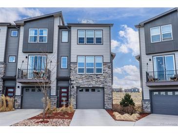 Modern townhome with stone accents, gray siding, attached garages, and small private balcony in a contemporary design at 4355 Cyan Cir # E, Castle Rock, CO 80109