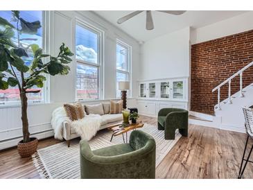 Bright living room with large windows, exposed brick, and hardwood floors create a welcoming space at 108 W Byers Pl # 106, Denver, CO 80223