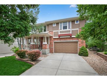 Charming two-story home with brick and siding, complemented by a well-manicured lawn and mature trees at 14682 W Amherst Pl, Lakewood, CO 80228