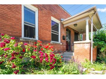 Charming brick home featuring a cozy covered porch and vibrant landscaping, including colorful roses at 22 E Bayaud Ave, Denver, CO 80209