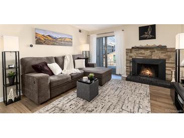 Inviting living room with a stone fireplace, a comfortable grey couch, and lots of natural light at 7665 E Eastman Ave # 107B, Denver, CO 80231