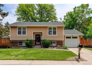 Charming two-story home with a well-manicured lawn, brick accents, and an attached garage at 8410 Gray St, Arvada, CO 80003