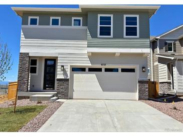 Two-story home showcasing a two car garage and a black front door with stone accents at 9237 Truckee Ct, Commerce City, CO 80022