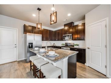 Modern kitchen features granite counters, stainless steel appliances, and seating at the kitchen island at 19714 W 93Rd Ln # C, Arvada, CO 80007