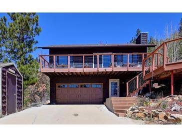 Charming two-story home features a spacious deck with mountain views and a convenient garage, nestled in a serene setting at 617 Hummingbird Trl, Idaho Springs, CO 80452