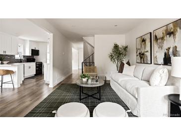 Bright living room featuring modern decor, wood floors, and an open layout into the kitchen at 9316 W Utah Ave, Lakewood, CO 80232