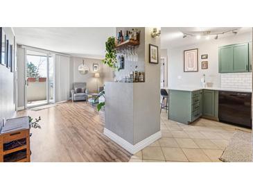 Bright living room featuring wood floors, a bar, balcony access, and an open floor plan to the kitchen at 601 W 11Th Ave # 311, Denver, CO 80204