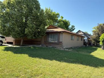 Charming single-story home with lush front lawn and mature shade tree on a sunny day at 8995 E Cornell Ave, Denver, CO 80231