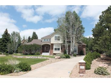 Charming two-story home with brick accents, arched entryway, lush landscaping and a long driveway at 8389 Owl Roost Ct, Parker, CO 80134