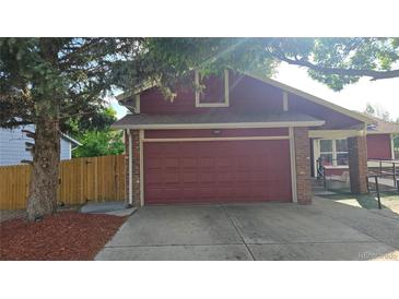 Exterior view of a single-Gathering home featuring a red facade, brick accents, and a two-car garage at 4543 Cathay St, Denver, CO 80249