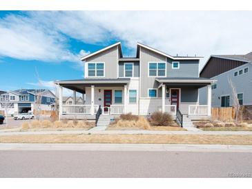 Charming two-story home with a covered front porch, a well manicured lawn, and an attractive red door at 21821 E 7Th Ave, Aurora, CO 80018