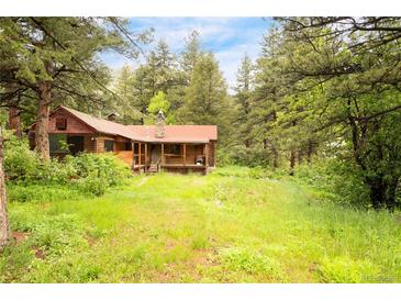 Charming cabin nestled among tall pines with a cozy front porch and lush, green surroundings at 35106 Boulder Canyon Dr, Boulder, CO 80302