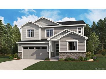 Charming two-story home with gray siding, stone accents, a well-manicured lawn and a two car garage at 245 Wooten Ave, Brighton, CO 80601