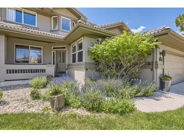 Beautiful front entrance with a well-manicured landscape, stone accents, and a charming walkway at 6435 Spotted Fawn Run, Littleton, CO 80125