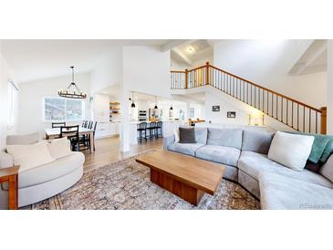 Open living area with vaulted ceilings, L-shaped sofa, and a cozy fireplace at 6495 S Wright St, Littleton, CO 80127