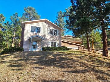 Charming two-story home featuring a covered entry, a wooden deck, and a tree-lined yard at 3841 Myers Gulch Rd, Kittredge, CO 80457