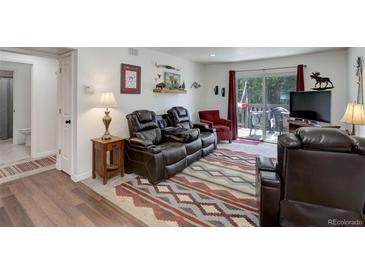 Comfortable living room featuring a leather reclining sofa set and outdoor access at 3550 S Harlan St # 249, Denver, CO 80235