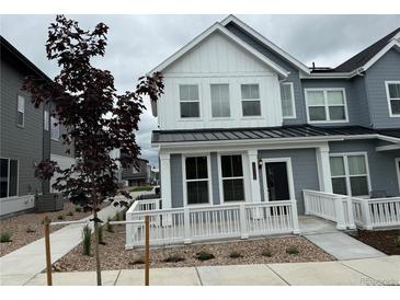 Charming gray townhome featuring a white fence, a well-maintained yard, and a welcoming entrance at 14556 W 91St Ave # D, Arvada, CO 80005