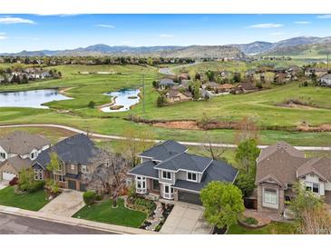 Expansive aerial view showcases a stunning home, lush golf course, serene lake, and majestic mountain backdrop at 6656 S Oak Cir, Littleton, CO 80127