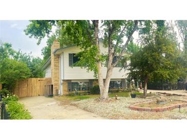 Charming home features brick and siding, a well-kept lawn and mature trees providing shade at 2633 Mather St, Brighton, CO 80601