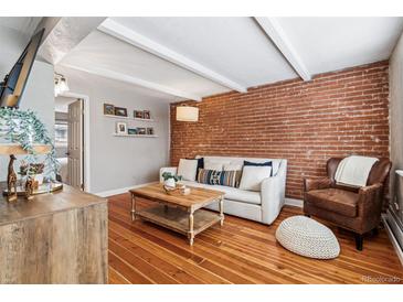 Inviting living room featuring exposed brick wall, wood floors, and comfortable seating arrangement with lots of natural light at 160 Jackson St # 5, Denver, CO 80206