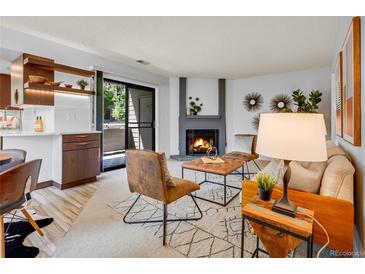 Cozy living room with a fireplace, stylish furniture, and a sliding door to the outside at 8378 S Upham Way # A102, Littleton, CO 80128