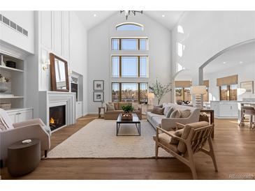 Bright living room with fireplace, large windows, and high ceilings provides a luxurious and inviting atmosphere at 948 Buffalo Ridge Rd, Castle Pines, CO 80108