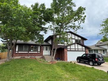 Charming two-story home features a manicured lawn, brick accents, and a two-car garage at 13052 W Asbury Pl, Lakewood, CO 80228