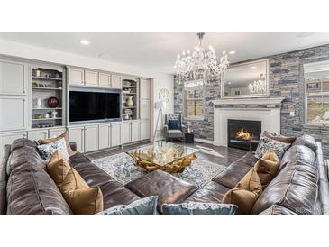 Inviting living room with a stone fireplace, elegant chandelier, and comfortable leather sectional sofa at 2627 Hillcroft Ln, Castle Rock, CO 80104