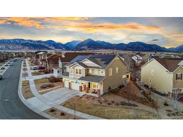Stunning two-story home featuring solar panels and mountain views at sunset at 19973 W 94Th Ln, Arvada, CO 80007