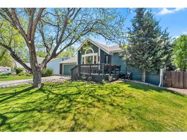 Inviting blue home with a charming front porch and lush green lawn under the shade of mature trees, creating a welcoming curb appeal at 8370 W Evans Pl, Lakewood, CO 80227