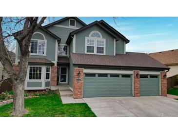Attractive two-story home with a well-maintained lawn, brick accents, and a two-car garage at 10052 Sage Sparrow Ct, Highlands Ranch, CO 80129