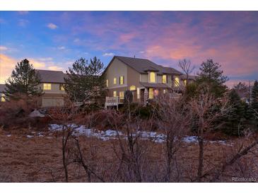 Inviting home with a large yard and mature trees against a colorful sunset at 8835 Edinburgh Cir, Highlands Ranch, CO 80129