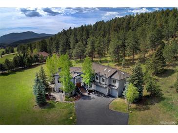 Expansive home featuring a multi-car garage, set against a backdrop of lush trees and mountain views at 2191 Baldy Ln, Evergreen, CO 80439