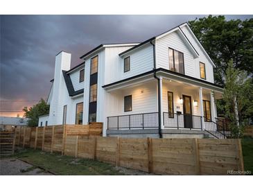 Stunning modern farmhouse exterior with a black-trimmed white facade and a charming wood fence at 3019 Chase St, Wheat Ridge, CO 80214