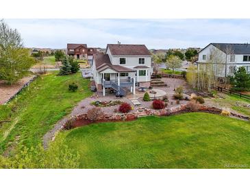 Lawn, landscaping, and a built-in stone fire pit make this backyard a welcoming outdoor living space at 42225 Kingsmill Cir, Elizabeth, CO 80107