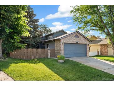 Charming two-story home boasts a brick facade, blue garage door, and well-manicured lawn, creating a welcoming curb appeal at 517 Chiswick Cir, Highlands Ranch, CO 80126
