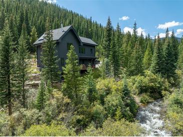 Secluded mountain home surrounded by a forest with a creek in the foreground at 379 Rainbow Rd, Idaho Springs, CO 80452