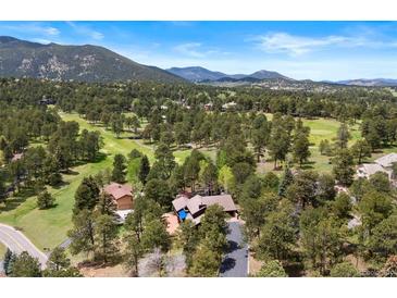 Stunning aerial view showcases the secluded home nestled within a lush golf course community surrounded by majestic mountains at 2851 Interlocken Dr, Evergreen, CO 80439
