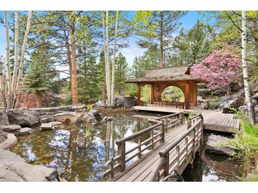Beautiful backyard pond with Japanese-style tea house and wooden bridge at 2851 Interlocken Dr, Evergreen, CO 80439
