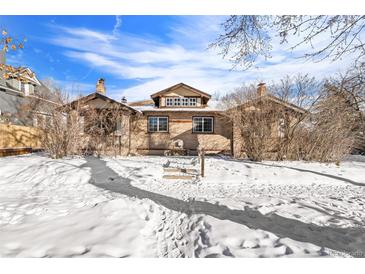 Inviting brick home with a dormer and chimney is surrounded by snow and bushes during the winter season at 2222-2224 Hooker St, Denver, CO 80211