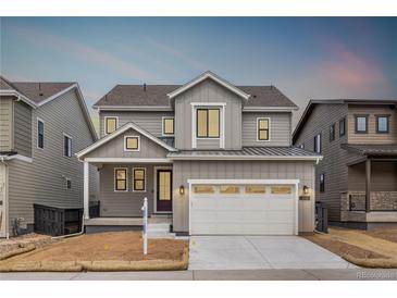 Charming two-story home with gray siding, a two-car garage, and a well-manicured front yard at 8903 Springsong Ln, Littleton, CO 80125