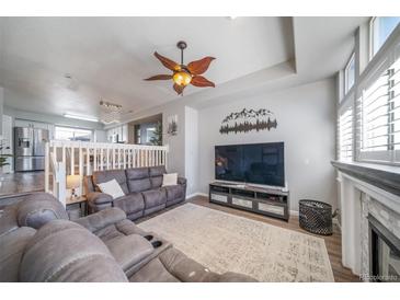 Cozy living room with plush seating, ceiling fan, fireplace, and mountain-themed wall decor at 12069 Monaco Ct, Brighton, CO 80602