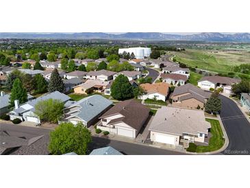 An aerial view of a well-maintained residential neighborhood with lush greenery and mountain views in the background at 23 Carla Way, Broomfield, CO 80020