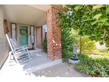 Charming front porch with rocking chairs, brick pillar, lovely landscaping and a decorative water feature at 6112 Alkire Ct, Arvada, CO 80004