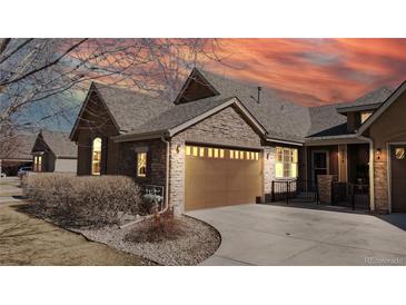 Charming home featuring a stone facade, a two-car garage, and well-maintained landscaping at 2238 Calais Dr # B, Longmont, CO 80504