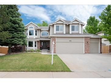 Charming two-story home featuring a three-car garage, manicured lawn, and mature landscaping at 11056 W Rowland Ave, Littleton, CO 80127